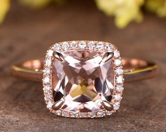 May include: A rose gold engagement ring with a square cushion-cut morganite gemstone surrounded by a halo of smaller diamonds.