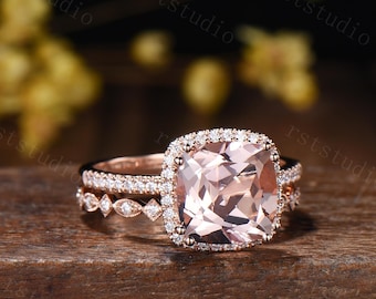 May include: A rose gold engagement ring set featuring a large, square-cut peach-colored gemstone surrounded by a halo of smaller stones. The set includes a matching band with delicate detailing.