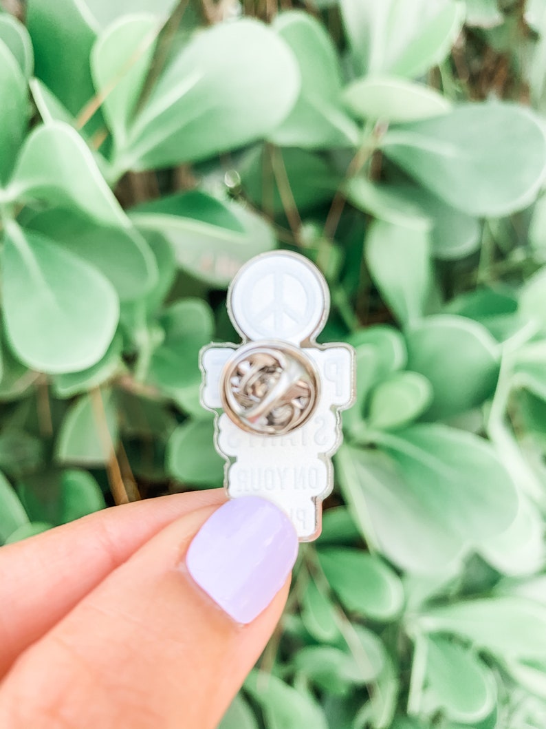 May include: White enamel pin with a peace sign and the text "Peace, Love, & Body Positivity" on it.