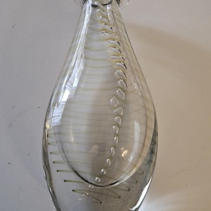 May include: Clear glass vase with a teardrop shape. The vase features horizontal white stripes and a vertical line of small bubbles. The top of the vase has a small opening.