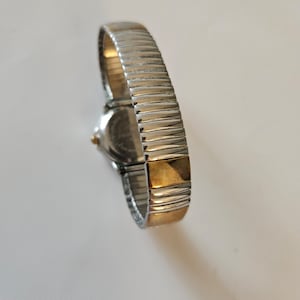 May include: A silver and gold two-tone watch with a metal band.