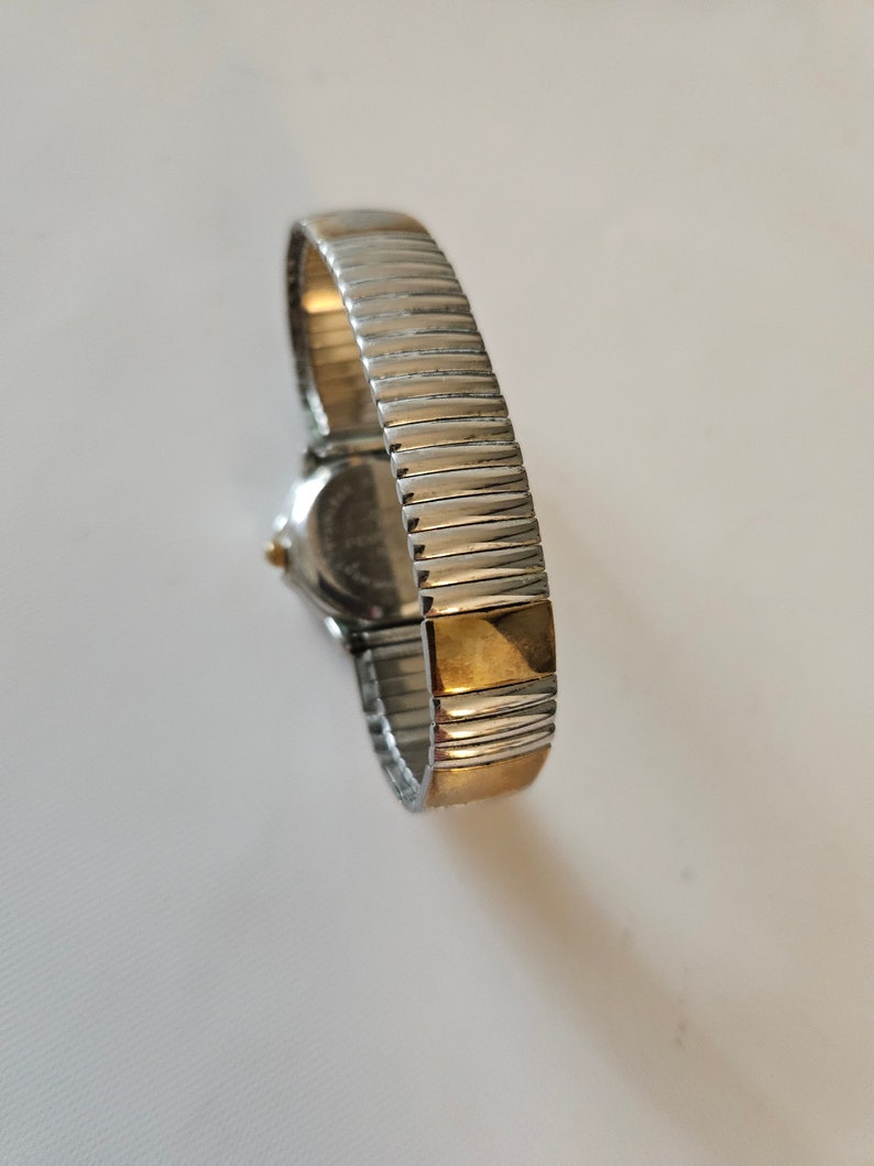 May include: A silver and gold two-tone watch with a metal band.