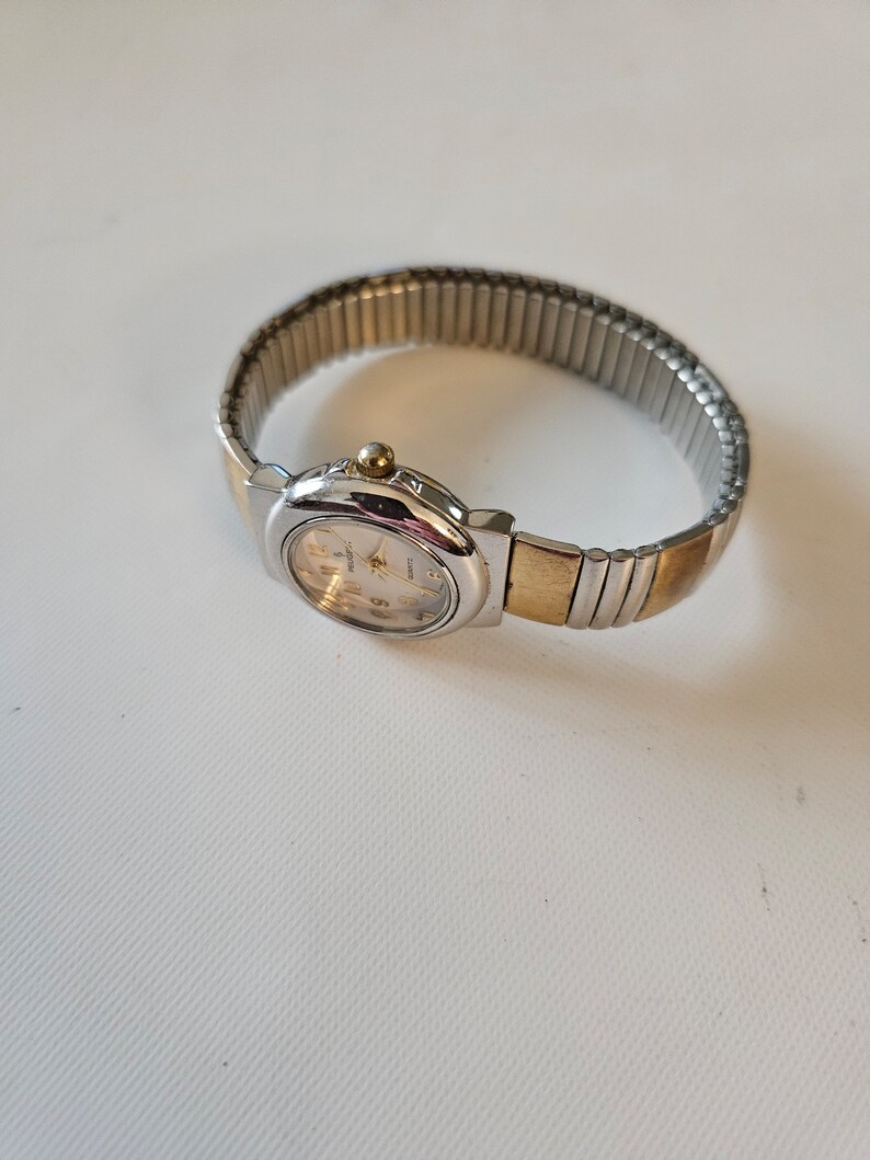 May include: A silver and gold two-tone watch with a white face and a metal band.