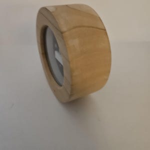 Puede incluir: Un reloj de madera con un acabado marr&oacute;n claro. El reloj tiene una forma rectangular redondeada con una esfera circular. La esfera es negra con marcas y manecillas blancas. El reloj est&aacute; hecho de madera.