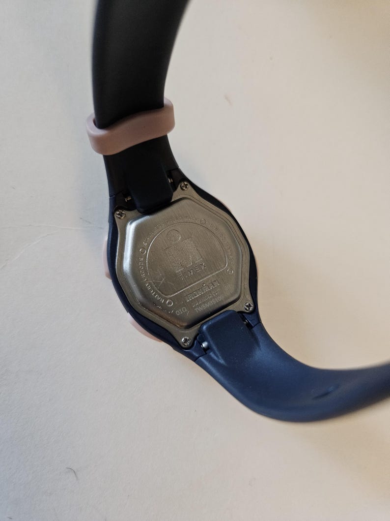 May include: A black and pink wristwatch with a silver face and the word "Timex" printed on it. The watch has a black band with a pink accent.