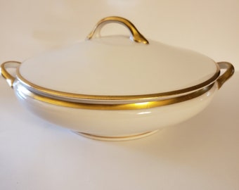 May include: White porcelain serving dish with a gold rim and a lid with a gold handle.