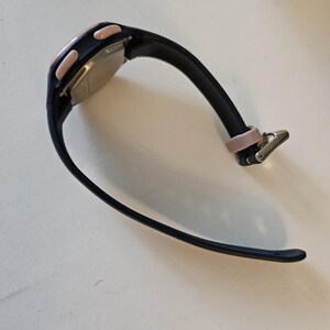 May include: Black and pink digital wristwatch with a black rubber band.