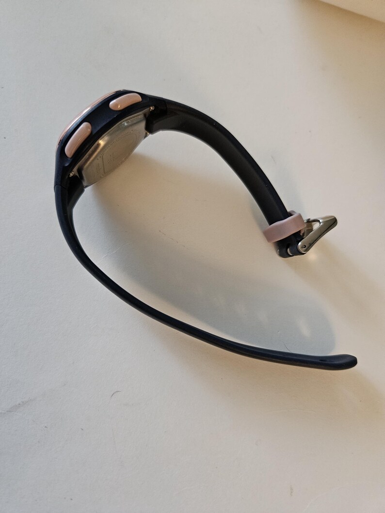 May include: Black and pink digital wristwatch with a black rubber band.