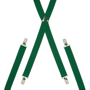 Puede incluir: Tirantes verdes con clips plateados. Los tirantes están cruzados en el centro y tienen un clip plateado en el punto donde se cruzan.