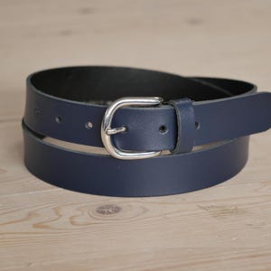 Op de afbeelding: Een donkerblauwe leren riem met een zilveren gesp.