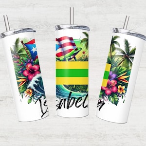 May include: Three white stainless steel tumblers with lids and straws. Each tumbler features a different design: a green frog on a tropical island with a Puerto Rican flag, a tropical island scene with palm trees and flowers, and a tropical island scene with a wave and flowers. The word "Isabel" is written on the tumbler with the frog.