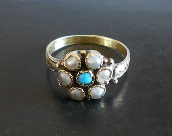 May include: A gold ring with a cluster of six white pearls and a turquoise stone in the center.