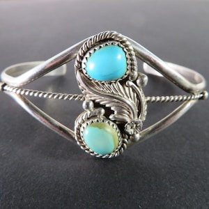 Puede incluir: Una pulsera de plata con dos piedras turquesa engastadas en un diseño de hoja.