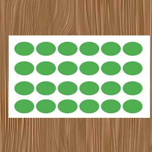 May include: A sheet of white paper with rows of green oval stickers. The stickers are evenly spaced and arranged in a grid pattern. The background is a wooden surface.