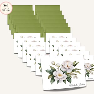 May include: A set of 12 floral greeting cards with matching green envelopes. Each white card features a watercolor illustration of white flowers and green leaves. The name "Michelle Jackson" is printed on the bottom of each card.