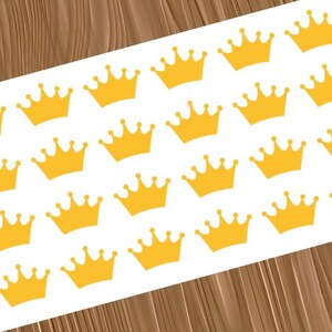 May include: A white rectangular sheet featuring a repeating pattern of twenty-four yellow crown stickers. Each crown is identical in shape, featuring five points with small circular tips, arranged in a grid across the surface of the sheet.