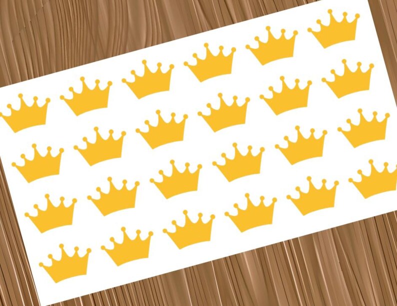 May include: A white rectangular sheet featuring a repeating pattern of twenty-four yellow crown stickers. Each crown is identical in shape, featuring five points with small circular tips, arranged in a grid across the surface of the sheet.