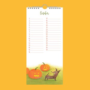 May include: A spiral-bound October calendar with a Halloween theme. It features a dachshund dog, carved pumpkins, and the word "October" in green script. The dates are listed vertically. The artist's name, "Doelens", is visible.