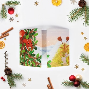 May include: A folded greeting card featuring a winter illustration of a red squirrel in a holly bush on the left panel and a small rabbit in a grassy field on the right panel, set against a snowy landscape with a soft, pale sky background.
