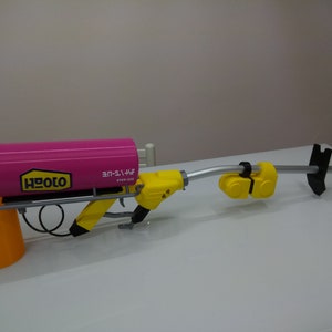 May include: A pink and yellow toy gun with a long barrel and a large tank on the front. The tank has the word "HEOLO" printed on it and the text "3F-11-46F" in Japanese characters.