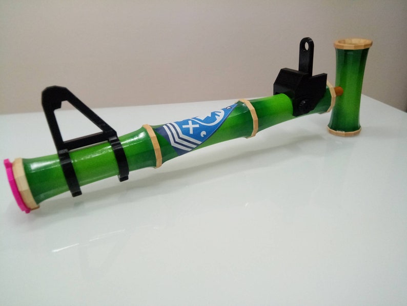 Puede incluir: Una pipa de bamb&uacute; verde y negra con un dise&ntilde;o azul y blanco. La pipa tiene un accesorio de metal negro en el extremo.