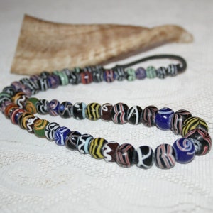 Peut inclure: Un collier de perles en verre coloré avec une variété de motifs et de couleurs, notamment le noir, le blanc, le bleu, le vert, le jaune et le rouge.