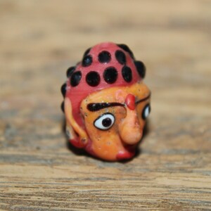 Może przedstawiać: Biały ceramiczny kubek z czarnym uchwytem i napisem "But First, Coffee" pogrubioną, czarną czcionką. Kubek jest ustawiony na rozmytym tle, sugerującym przytulne otoczenie.