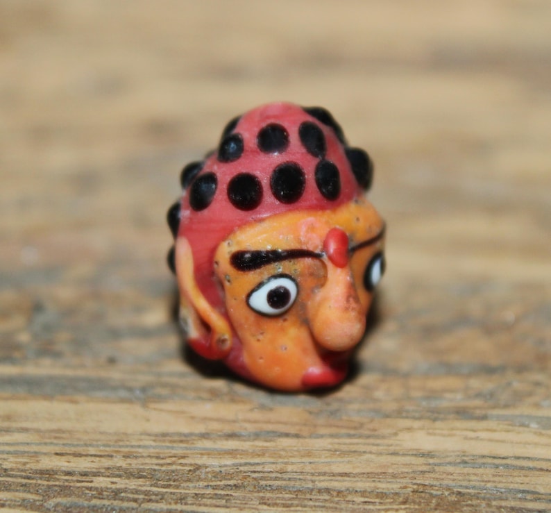 Może przedstawiać: Biały ceramiczny kubek z czarnym uchwytem i napisem "But First, Coffee" pogrubioną, czarną czcionką. Kubek jest ustawiony na rozmytym tle, sugerującym przytulne otoczenie.