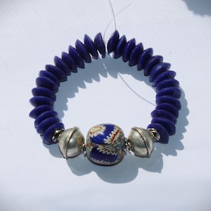 Könnte beinhalten: Ein blaues Perlenarmband mit einer silbernen und blauen Perle mit Muster in der Mitte.