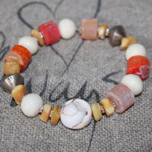 May include: A bracelet made of white, orange, and brown beads with a small seashell charm.