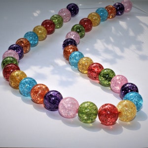 May include: A strand of colourful, sparkly beads. The beads are round and translucent, with a variety of colours including pink, blue, green, yellow, and purple.