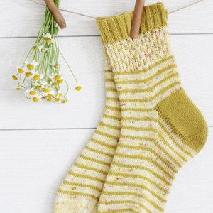 May include: A pair of yellow and white striped socks with a speckled pattern hanging on a clothesline with wooden pegs.
