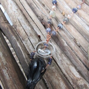 May include: A black bird skull pendant necklace with a copper chain and blue and clear glass beads.