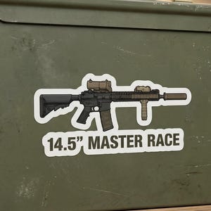 Peut inclure: Un coffre à munitions en métal vert olive avec un autocollant d'un fusil qui dit "14.5" MASTER RACE". La boîte est sur une surface en bois avec des outils et des accessoires.