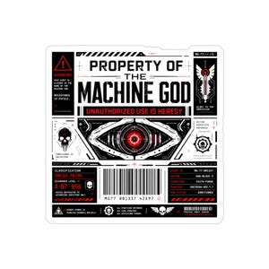 May include: A white sticker with black and red graphics, featuring the text "PROPERTY OF THE MACHINE GOD." The design includes a stylized eye, skull, barcode, and various technical symbols. The sticker also has the text "UNAUTHORIZED USE IS HERESY."