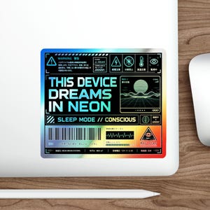 以下が含まれることがあります： 青と緑のグラデーションで「THIS DEVICE DREAMS IN NEON」と書かれたホログラフィックステッカー。ステッカーには、脳や波形など、日本語のテキストと技術的な記号も含まれています。