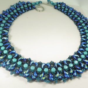 Könnte beinhalten: Eine blaue und türkisfarbene Perlenkette mit einem silbernen Verschluss. Die Kette besteht aus kleinen, tropfenförmigen Perlen und runden Perlen.