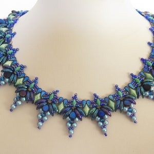 May include: A blue and green beaded necklace with a geometric design. The necklace is made with small, iridescent beads and has a pointed, starburst shape.