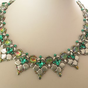 May include: A silver and green beaded necklace with a geometric design. The necklace features iridescent green beads and silver beads in a repeating pattern.