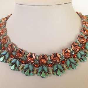 May include: A multi-strand necklace with a graduated design featuring copper and teal beads. The necklace is made with a variety of bead shapes and sizes, including teardrop, round, and faceted beads.