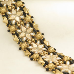 Peut inclure: Un bracelet en perles dorées, noires et blanches avec un motif géométrique. Le bracelet est composé de perles de différentes tailles et formes, notamment des perles rondes, en forme de larme et en forme d'étoile.