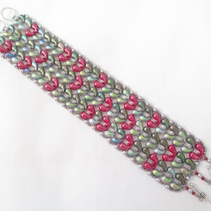 May include: A beaded bracelet featuring a pattern of red and green heart-shaped beads. The bracelet has a silver-colored clasp and connecting rings. The beads are arranged in rows and bordered by smaller, iridescent beads.