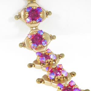 May include: A gold bracelet with pink and purple iridescent beads. The bracelet is made with small, round beads and larger, faceted beads.