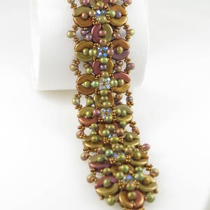 May include: A gold and green beaded bracelet with a floral design and a silver clasp.