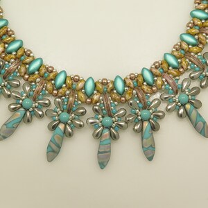 Peut inclure: Un collier de perles turquoise et argent avec un motif floral. Le collier a un design multi-brins avec une rang&eacute;e de perles turquoise et argent en bas.