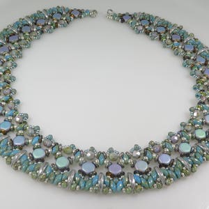 May include: A multi-strand necklace featuring turquoise, silver and iridescent blue beads. The necklace is crafted with a range of bead shapes and sizes, resulting in a distinctive and eye-catching design.