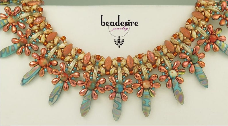 Peut inclure: Un collier de perles avec un design multi-rangs pr&eacute;sentant un motif r&eacute;p&eacute;titif de petites fleurs et de perles en forme de larme. Le collier est r&eacute;alis&eacute; avec une vari&eacute;t&eacute; de couleurs, notamment le p&ecirc;che, la cr&egrave;me, le turquoise et le cuivre.