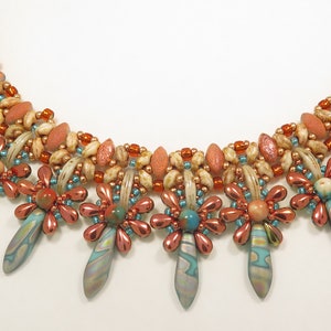 Peut inclure: Un collier multi-rangs avec un design perl&eacute; en cuivre, turquoise et cr&egrave;me. Le collier a un motif floral avec un pendentif en forme de larme.