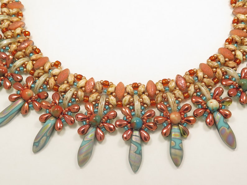 Peut inclure: Un collier multi-rangs avec un design perl&eacute; en cuivre, turquoise et cr&egrave;me. Le collier a un motif floral avec un pendentif en forme de larme.