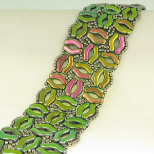 May include: A beaded bracelet featuring a geometric design in shades of green, pink, and silver.